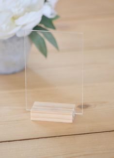 a clear acrylic block sitting on top of a wooden table next to a white flower