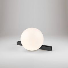 a white light sitting on top of a black stand next to a gray wall and floor