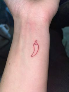 a small red chili pepper tattoo on the wrist