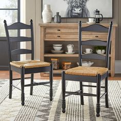 two wooden chairs sitting on top of a rug