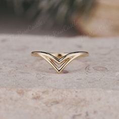 a gold ring sitting on top of a stone surface next to a potted plant