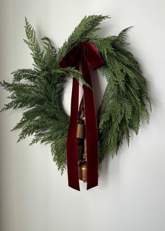 a wreath hanging on the wall with a red ribbon