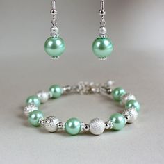 A contemporary 2-piece jewellery set featuring faux glass pearls in light mint green colour and bright silver plated stardust beads. Perfect for any occasion, weddings and parties or as a gift. Set contains beaded bracelet and a pair of drop earrings. Organza gift bag included!  Please note that although I take a great care to keep the colors on the photographs as close to reality as possible, they may look slightly different on different monitors. Materials used: Faux glass earls, green ( 10 mm Mint Green Jewelry, Bridesmaid Jewelry Set, Light Mint Green, Beaded Wedding, Bridesmaid Jewelry Sets, Jewellery Set, Organza Gift Bags, Green Colour, Wedding Jewelry Sets