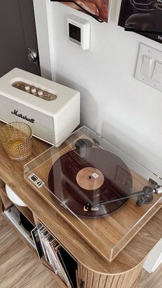 a record player sitting on top of a wooden table next to a wall mounted speaker