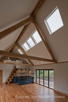 an empty room with wooden floors and skylights