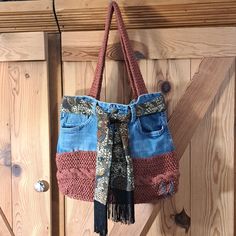 a purse hanging on the side of a wooden door with a scarf tied around it