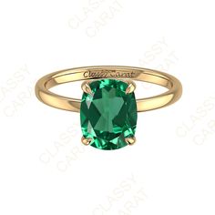 a gold ring with a green stone in the center and engraving on the side,