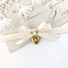 This dainty choker necklace is handmade with a soft velvet ribbon in a warm white hue. It features a delicate lace silk satin ribbon bow and a dainty vintage brass heart locket with a tiny pearl inset. See last photo showing coordinating designs... a fun group gift for you and your besties!  * Size ~ Adjustable length 12 - 15 inches with extender chain  Please check your neck size carefully as I do not accept returns or exchanges on these necklaces. Contact me prior to purchase. I am happy to ad Elegant Heart Shaped Choker For Valentine's Day, Elegant Heart-shaped Choker For Valentine's Day, Vintage Ribbon Choker As A Gift, Vintage Ribbon Choker As Gift, Elegant Heart Charm Choker For Valentine's Day, Elegant Heart Choker With Heart Charm, Elegant Heart Shaped Choker With Heart Charm, Elegant Heart Charm Heart Shaped Choker, Elegant Heart Charm Choker For Gift