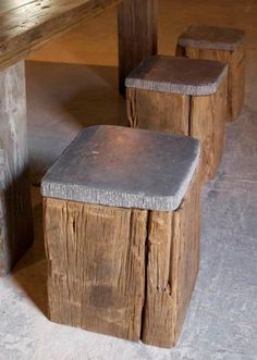 two wooden stools sitting next to each other on top of a cement covered floor