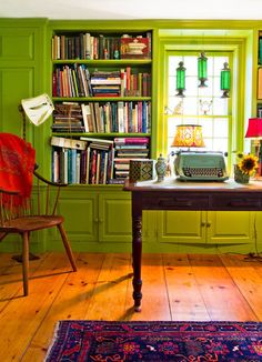 a green room with a desk, chair and bookshelf filled with lots of books