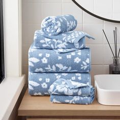 blue towels stacked on top of each other in front of a bathroom mirror and sink