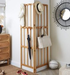 a coat rack with umbrellas and hats on it in a room next to a dresser