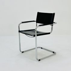 a black leather chair sitting on top of a white floor next to a metal frame