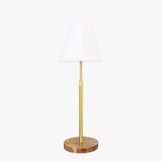 a gold lamp with a white shade on it's base and a wooden base