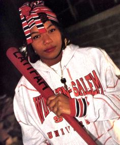 a woman holding a red baseball bat in her right hand and wearing a striped headband