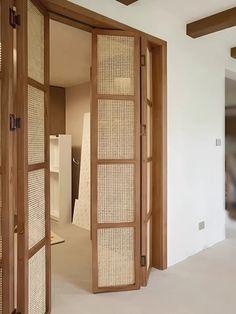 an open wooden door in a room with white walls and carpeted flooring on the ground