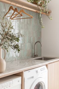 a washer and dryer in a kitchen with green tiles on the wall behind it