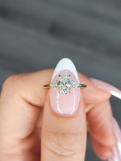 a woman's hand holding a pink and white manicure with a diamond ring on it