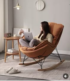 a woman sitting in a rocking chair using a laptop