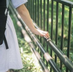 a woman is holding onto the rail of a metal fence with her hand on it