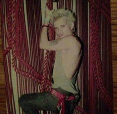 a young man sitting on top of a wooden floor next to red ropes and chains