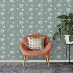 an orange chair sitting in front of a green wallpaper with white flowers on it