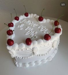 a white cake topped with cherries on top of a table