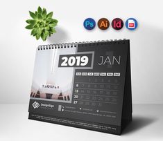 a desk calendar sitting on top of a table next to a potted plant