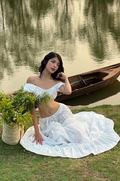 a woman sitting on the grass next to a boat