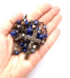 "Beautiful handcrafted vintage-inspired Catholic Heirloom Rosary with Blue Orange Sodalite gemstones. Pater beads are Lapis gemstones with Antique Brass bead caps. Each bead is wire wrapped using 20-gauge Vintage Bronze colored wire for strength and durability. The intricate design of the crucifix and center are antique-styled bronze replicas giving the Rosary that \"Old World\" finish. Specifics: *Ave Beads: Blue Orange Sodalite gemstones 6mm *Pater Beads: Lapis gemstones 10mm *Caps and Spacers The Rosary, Miraculous Medal, Bead Caps, Bronze Color, Rosary, Old World, Antique Bronze, Blue Orange, Wire Wrapped