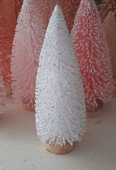 small white and pink christmas trees are in front of each other on a countertop