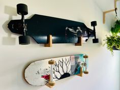 two skateboards are hanging on the wall next to a potted plant and vase