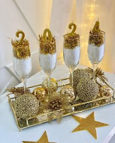 gold and white decorations on a tray with wine glasses filled with confetti, sprinkles and stars