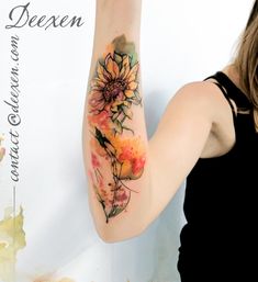 a woman with a sunflower tattoo on her arm and hand is pointing at the wall