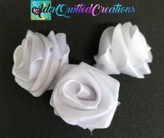 three white fabric flowers sitting on top of a black countertop next to each other