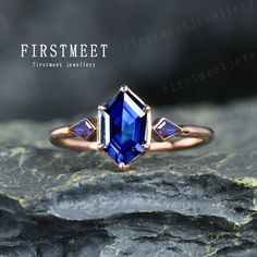 a close up of a ring with a blue stone in the middle and two diamonds on top