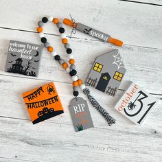 some halloween decorations are laying out on a table with white wood planks and black and orange beads