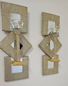 two decorative mirrors mounted to the side of a wall next to each other, one with a candle holder on it