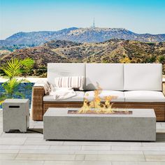 a fire pit sitting on top of a patio next to a white couch and table