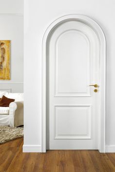 an arched door in a white room with hardwood flooring and rug on the floor