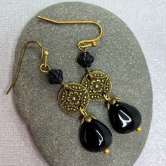 Long black glass teardrop earrings. Richly detailed antiqued brass finish Mandala connectors suspend black Czech glass teardrop beads. Perfect earrings to go with everything from jeans to dress up. A wardrobe must-have! Hypoallergenic ear wires (nickel and lead free). Choose ear wires at checkout.  Artisan glass beads produced in small quantities in the Czech Republic A gift for you or someone special, earrings are carded and in an organza bag. Available in ANTIQUE COPPER finish here: https://ww Black Bohemian Teardrop Dangle Earrings, Nickel-free Brass Beaded Teardrop Earrings, Nickel-free Teardrop Beaded Brass Earrings, Nickel-free Brass Teardrop Beaded Earrings, Handmade Black Bohemian Teardrop Earrings, Vintage Teardrop Beaded Earrings Nickel Free, Nickel-free Vintage Teardrop Beaded Earrings, Nickel-free Teardrop Vintage Beaded Earrings, Black Bohemian Teardrop Earrings For Gift