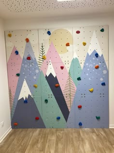 an indoor climbing wall in a room with wood flooring and painted mountains on it