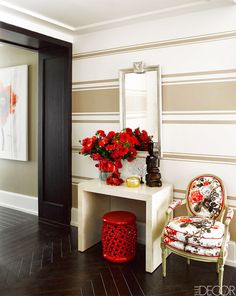 a room with a chair, mirror and flowers on the table in front of it