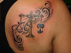 the back of a woman's shoulder with a libra symbol tattoo on it