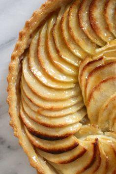 an apple pie with sliced apples in it on a marble counter top, ready to be eaten