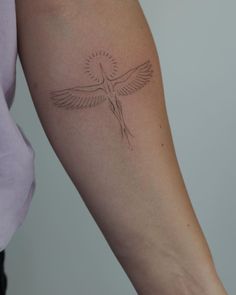 a woman's arm with a small bird tattoo on the left side of her arm