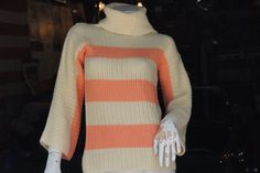 the mannequin is wearing an orange and white striped sweater with gloves on it