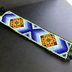 a beaded bracelet with an orange, yellow and blue design on the end is sitting on a table