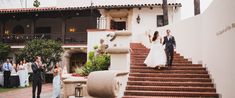 the bride and groom are walking down the stairs at their wedding reception in front of an elegant building