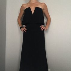 a woman in a long black dress posing for the camera with her hands on her hips